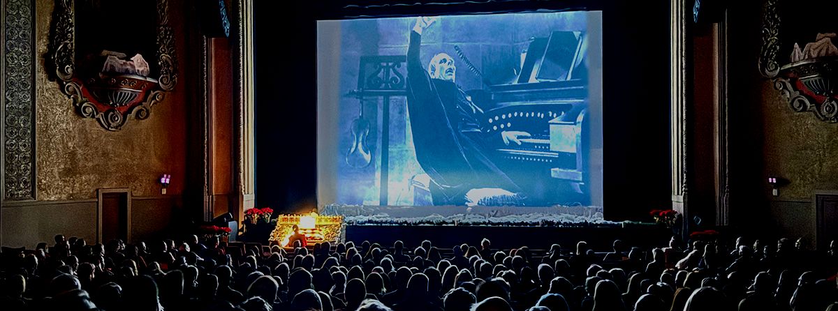 Interior of Balboa Theater showing screen with silent film 'Phantom of the Opera' and the organist performing below.