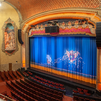 Photograph of an orchestra on stage performing at the Balboa Theatre, perspective is from upper right side of audience